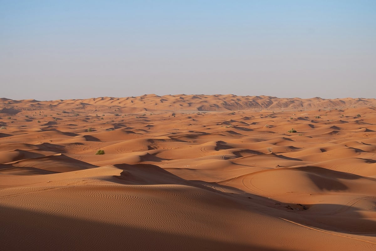كثبان رملية متموّجة في الصحراء خارج دبي تحت سماء صافية