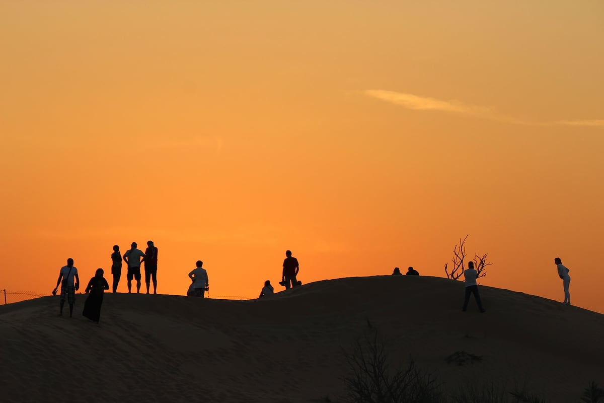 A group watching the sunset from the top of a dune outside Dubai