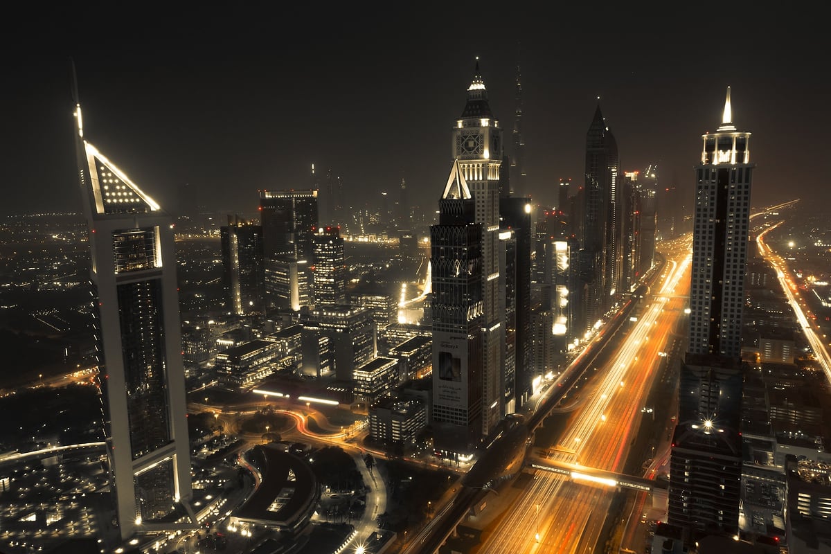 شارع الشيخ زايد وأبراج الإمارات ليلًا، وحركة السير تتجه نحو وسط المدينة